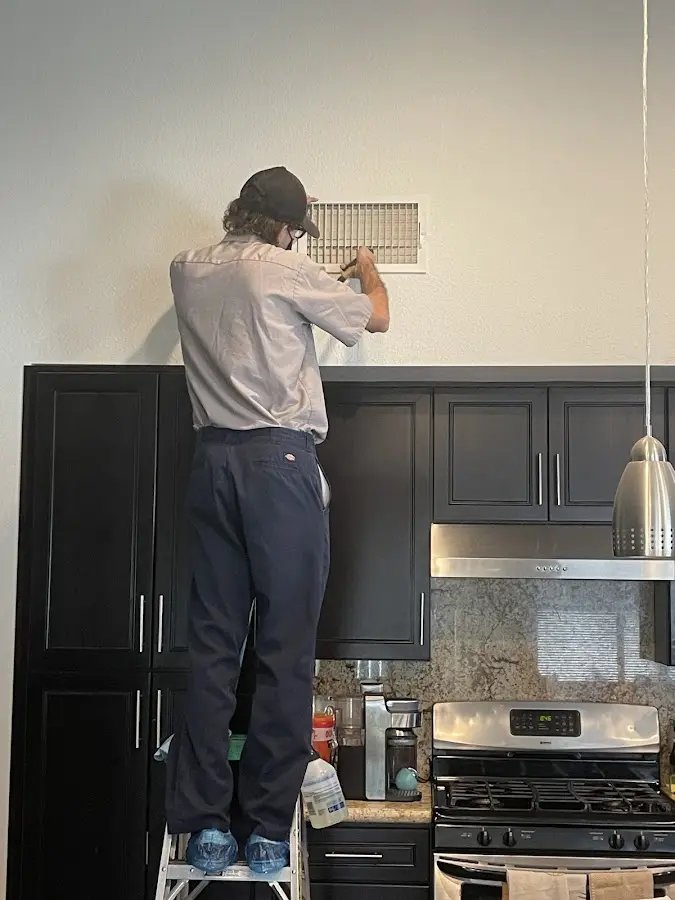 Technician inspecting an air vent during HVAC service in Millcreek